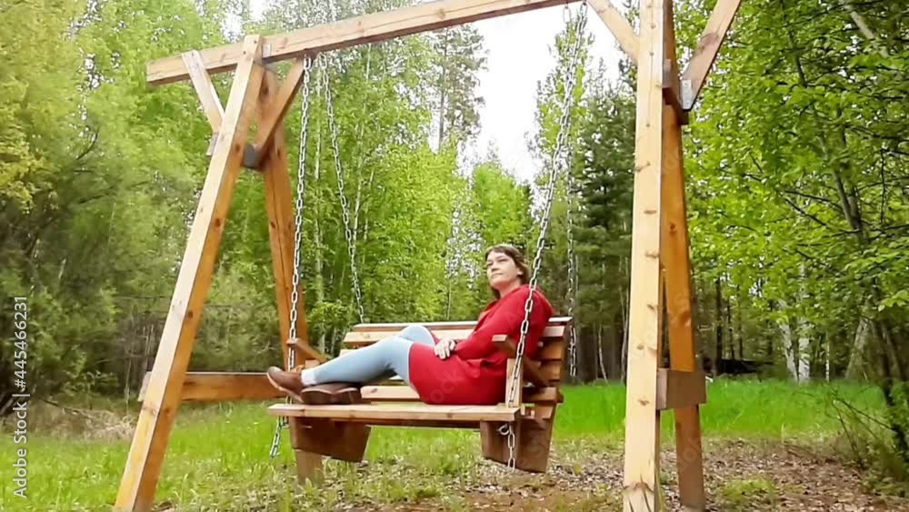 A 40-year-old woman swings on a wooden swing in an eco-hotel