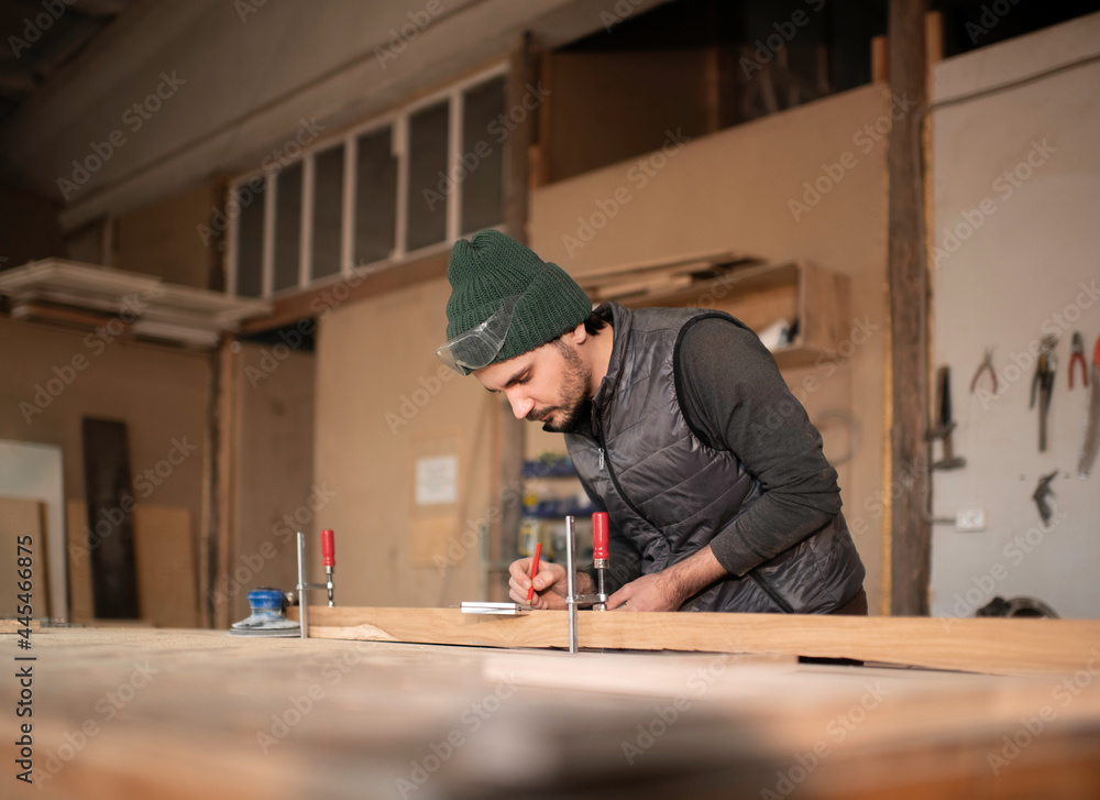 Male carpenter making marks on plank Male carpenter making marks on plank