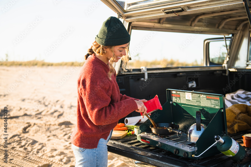 Young woman tailgate cooking while beach car camping alone Young woman tailgate cooking while beach car camping alone