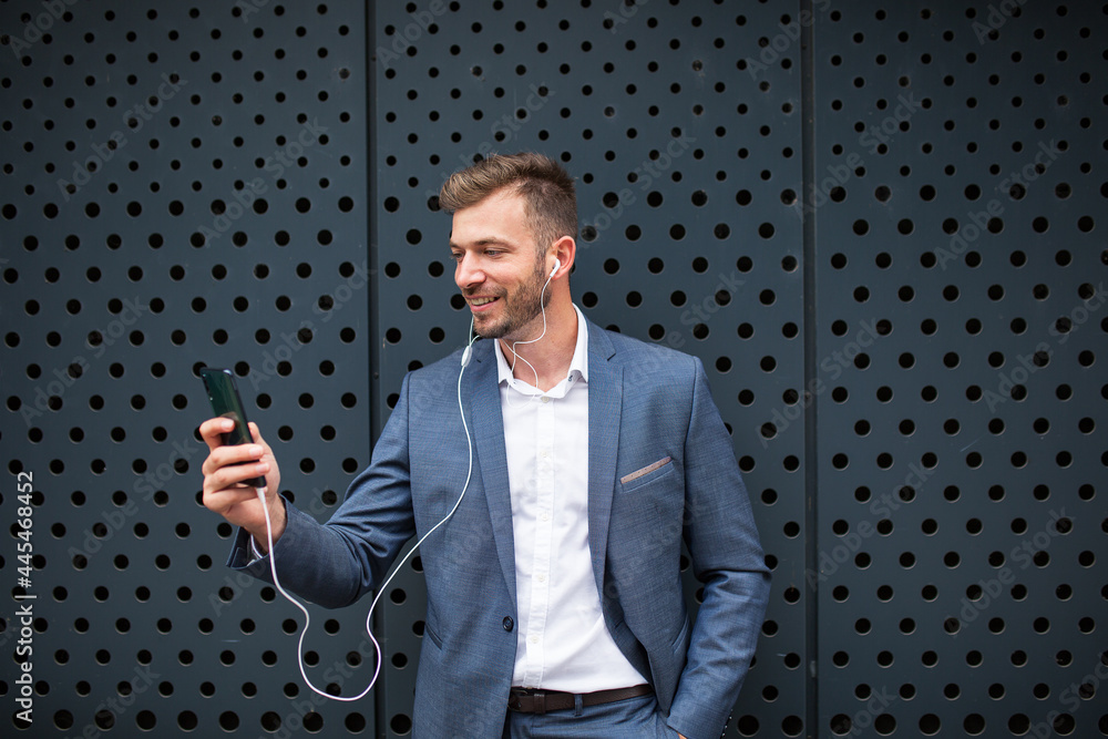 Naklejka premium Handsome businessman wearing earphones talking on mobile phone