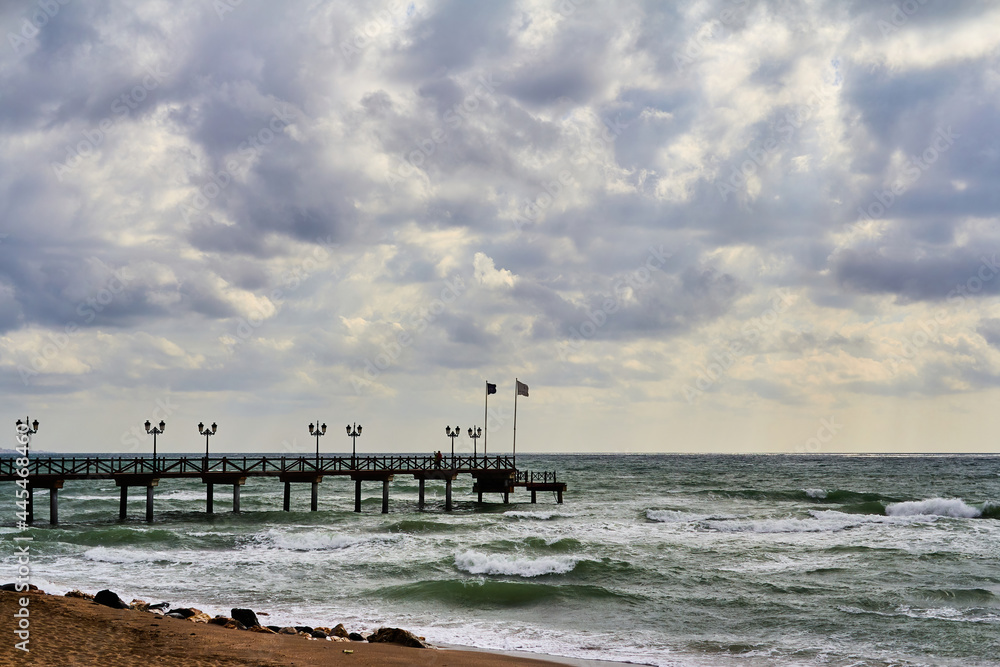Marbella, Malaga, Spain -23 February 2016.Sand beach and wooden pier on the Costa del Sol, tourist town of Marbella, Spain Marbella, Malaga, Spain -23 February 2016.Sand beach and wooden pier on the Costa del Sol, tourist town of Marbella, Spain
