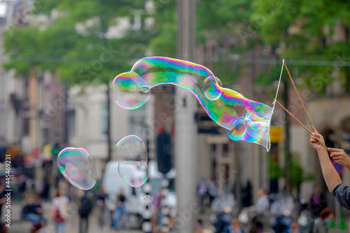 Canvas Print Outdoor recreation and activity concept, Selective focus of colourful bubbles floating in the air, Rainbow soap foam with blurred of peopoles in Dam Square as background, Amsterdam, Netherlands