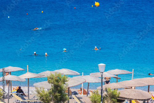 Сane umbrellas and sunbeds on an empty beach resort - vacation concept on Greece islands in Aegean and Mediterranean seas. Enidriou Beach in Rhodes city.