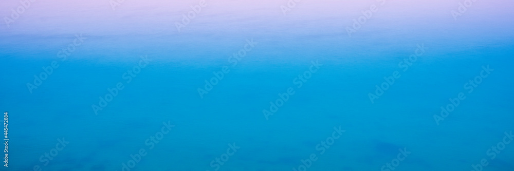 Abstract Seascape Blue and Pink Background Photo. Blurred Ocean and Rising Sun Rays on a Foggy Morning. Soft Pastel Space for Text and Design. Abstract Seascape Blue and Pink Background Photo. Blurred Ocean and Rising Sun Rays on a Foggy Morning. Soft Pastel Space for Text and Design.