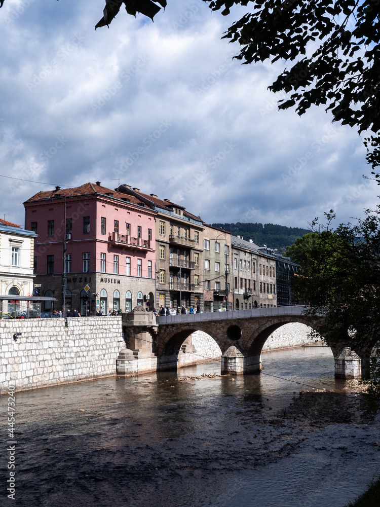 Obraz premium Peek to the Latin Bridge, through some trees, over the Miljacka river. Sarajevo, Bosnia and Herzegovina.