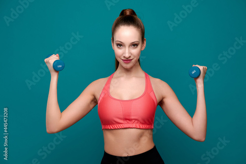 Athletic woman wearing fitness clothes exercising with dumbbell indoor © khmelev