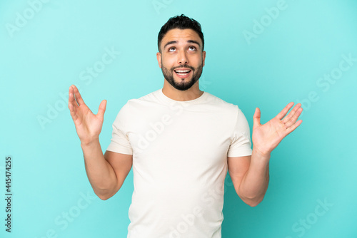 Young arab man isolated on blue background stressed overwhelmed