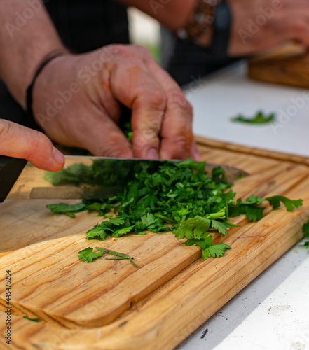 manos cortando vegetales sobre tabla de madera.

anos cortando cebolla, chile , jitomate, cilantro 