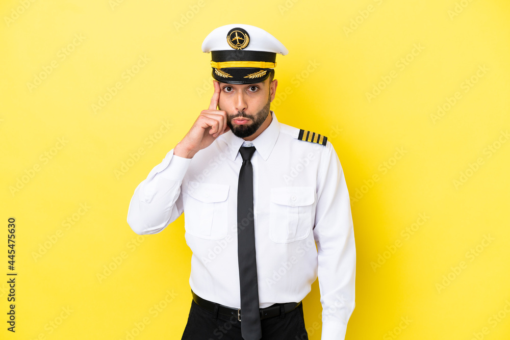 Airplane arab pilot man isolated on yellow background thinking an idea Airplane arab pilot man isolated on yellow background thinking an idea