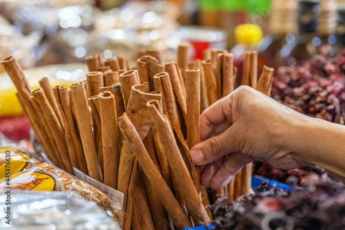 Woman buying cinammon sticks  in market. Close up of hands of latin woman buying spices