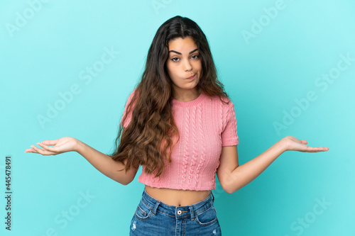 Young caucasian woman isolated on blue background having doubts while raising hands