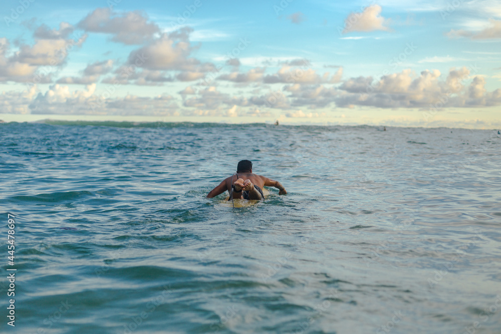 man swims away on top of his surfboard in the sea during the daytime