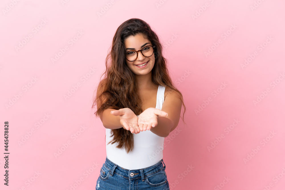 Young caucasian woman isolated on pink background holding copyspace imaginary on the palm to insert an ad Young caucasian woman isolated on pink background holding copyspace imaginary on the palm to insert an ad