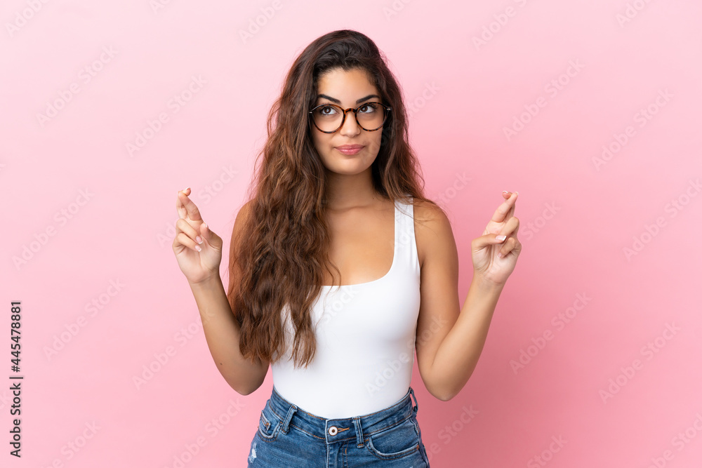 Young caucasian woman isolated on pink background with fingers crossing and wishing the best Young caucasian woman isolated on pink background with fingers crossing and wishing the best