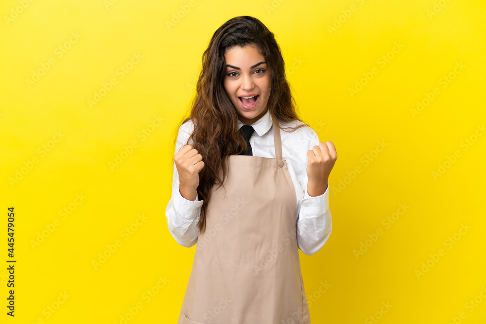 Young caucasian restaurant waiter isolated on yellow background celebrating a victory in winner position Young caucasian restaurant waiter isolated on yellow background celebrating a victory in winner position
