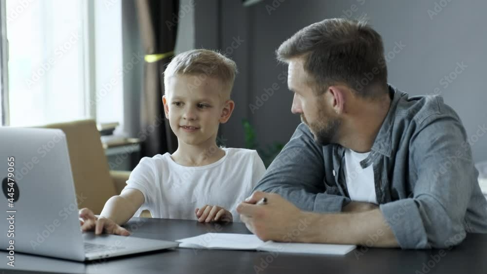 Smiling son thanking father for his help in doing homework at home Smiling son thanking father for his help in doing homework at home