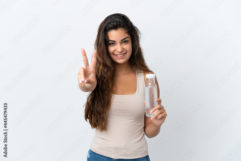 Young caucasian woman with a bottle of water isolated on white background smiling and showing victory sign Young caucasian woman with a bottle of water isolated on white background smiling and showing victory sign