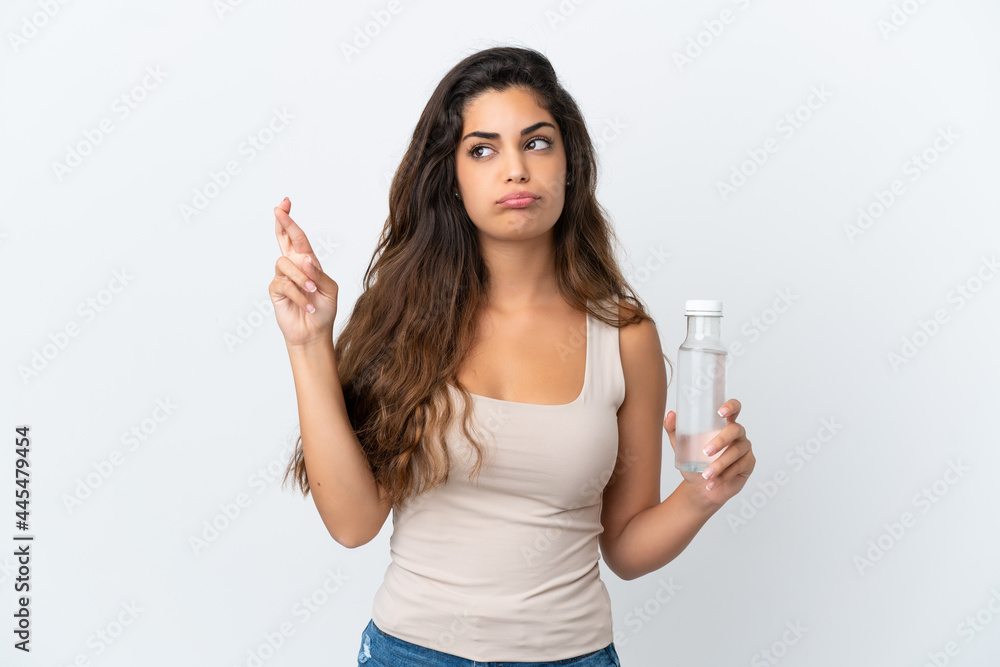 Young caucasian woman with a bottle of water isolated on white background with fingers crossing and wishing the best Young caucasian woman with a bottle of water isolated on white background with fingers crossing and wishing the best