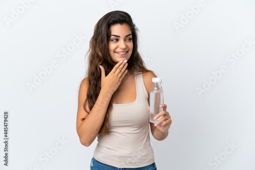 Young caucasian woman with a bottle of water isolated on white background looking up while smiling © luismolinero