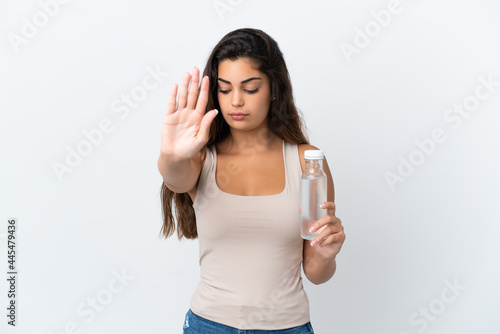 Young caucasian woman with a bottle of water isolated on white background making stop gesture and disappointed