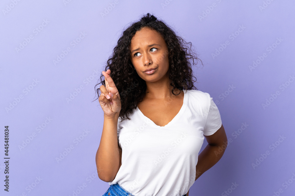 Fototapeta premium Teenager cuban girl isolated on purple background with fingers crossing and wishing the best