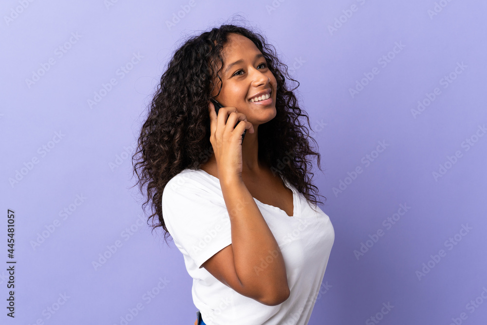 Teenager cuban girl isolated on purple background keeping a conversation with the mobile phone with someone Teenager cuban girl isolated on purple background keeping a conversation with the mobile phone with someone
