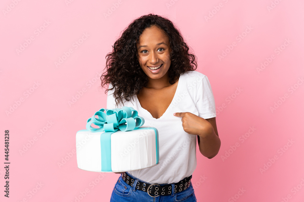 Pastry chef holding a big cake isolated on pink background with surprise facial expression Pastry chef holding a big cake isolated on pink background with surprise facial expression