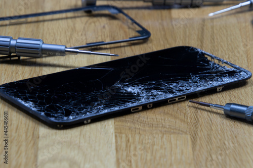 Bangkok, Thailand - 29 May 2021: Close-up shot of the broken screen of the iPhone 11 with tools waiting for repair on a wooden floor. photo