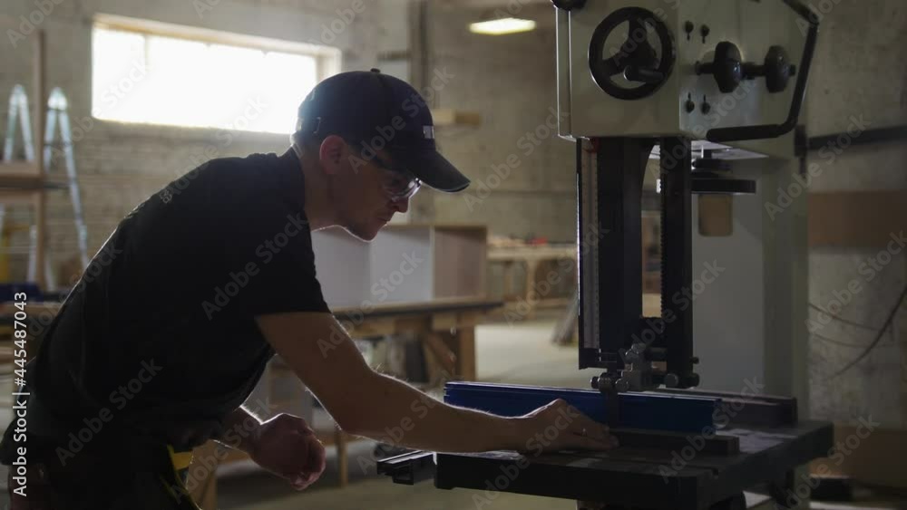 Carpentry workshop - worker cutting wooden details with an automatic saw Carpentry workshop - worker cutting wooden details with an automatic saw