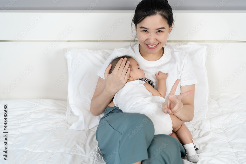 mother holding newborn baby sleeping in her arm on bed mother holding newborn baby sleeping in her arm on bed