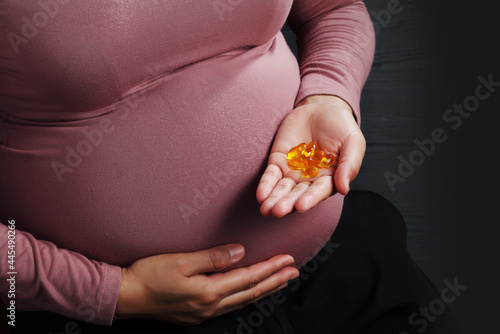 Close up pregnant woman holding medicine on black background