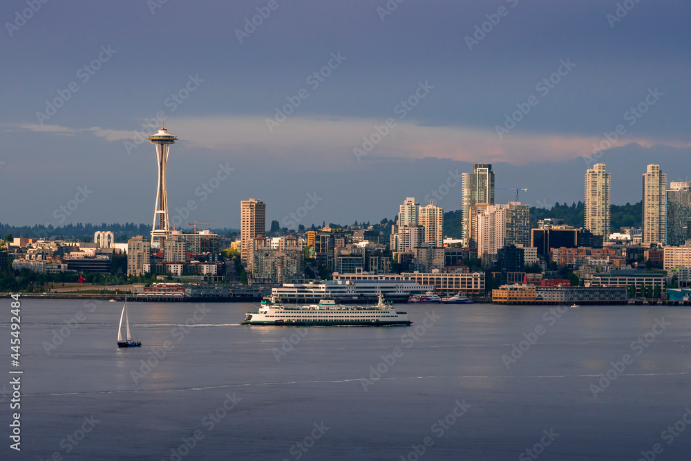 A sailboat and Washington State Ferry boat sail on Puget Sound as the famous Space Needle and skyscrapers rise above Elliott Bay in Seattle.