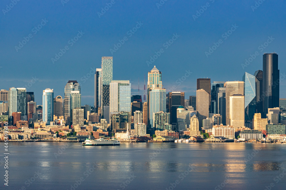 A Washington State Ferry crosses Elliott Bay as the downtown Seattle skyline rises above Puget Sound on a beautiful evening in the Pacific Northwest.