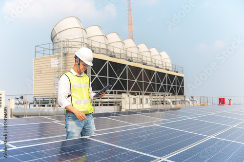 Engineer holding notebook sets the operation of the solar panel on the roof of the building to work at full efficiency.Using solar cells is energy saving. Renewable energy concepts. © tonjung