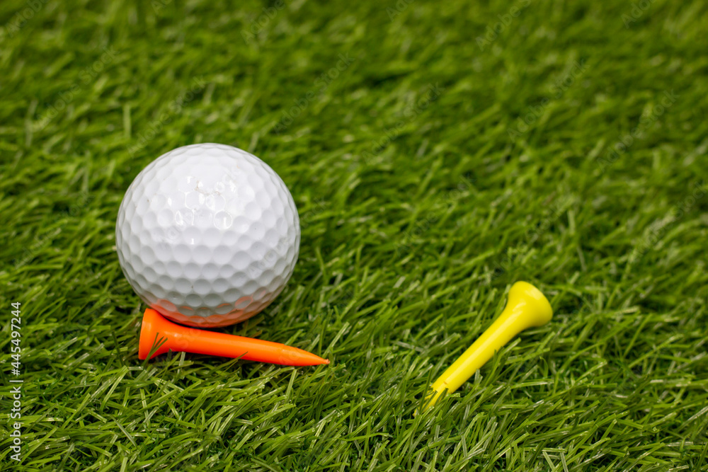 Golf ball with yellow and orange are on green grass Golf ball with yellow and orange are on green grass