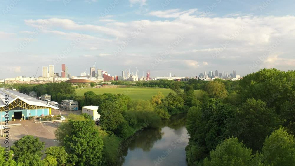 meadows along river and city skyline in distance. Descending footage to water surface. Hiding of view behind trees. meadows along river and city skyline in distance. Descending footage to water surface. Hiding of view behind trees.