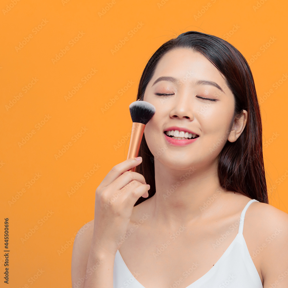 Beauty Asian Girl applying powder brush on her cheek Beauty Asian Girl applying powder brush on her cheek