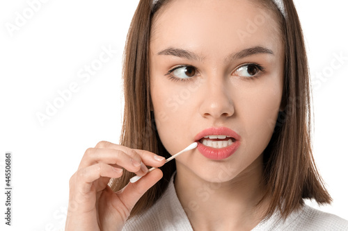 Young woman with cotton bud on white background