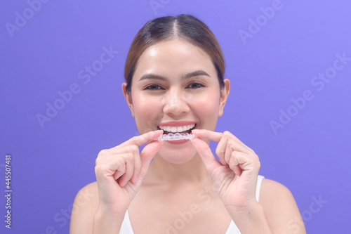 Young smiling woman holding invisalign braces in studio, dental healthcare and Orthodontic concept..