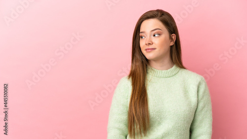 Teenager girl over isolated pink background making doubts gesture looking side © luismolinero