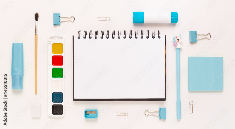 Top view of modern white blue office desktop with school supplies and stationery on table around empty space for text. Back to school concept flat lay with mockup Top view of modern white blue office desktop with school supplies and stationery on table around empty space for text. Back to school concept flat lay with mockup