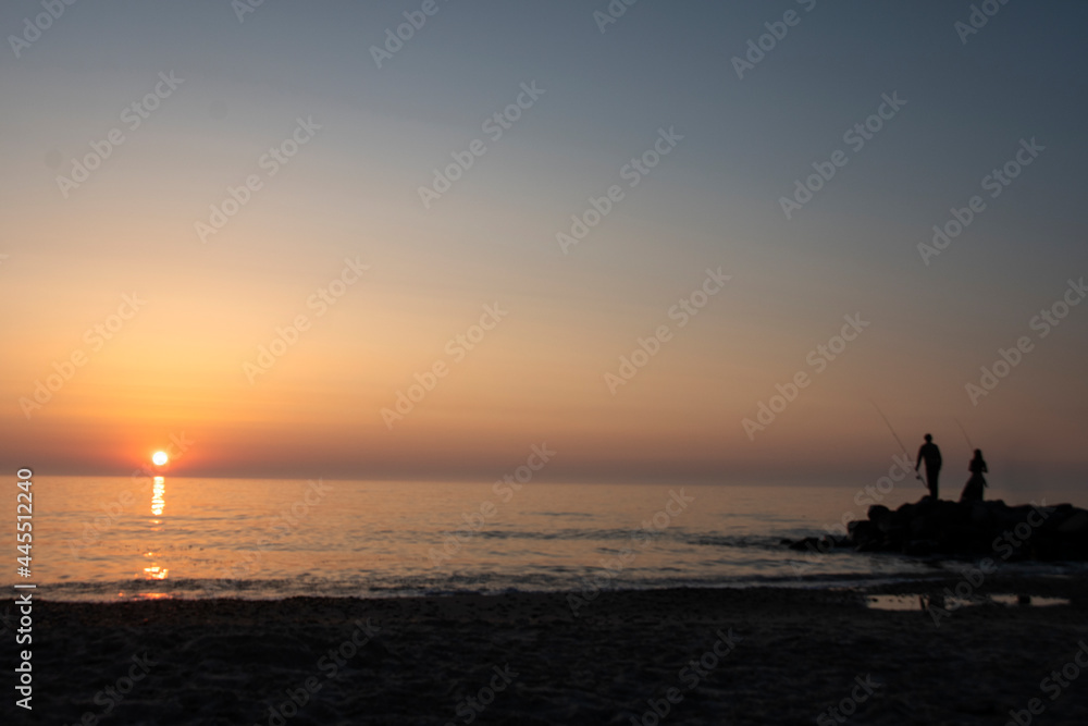 A boy and a girl fishing in sunset in Skagen in Denmark