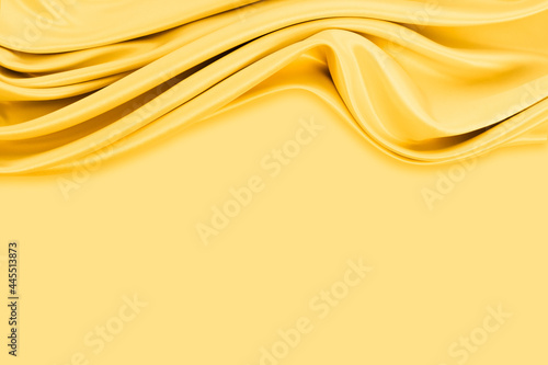 Beautiful elegant wavy yellow satin silk luxury cloth fabric texture with monochrome background design. Copy space
