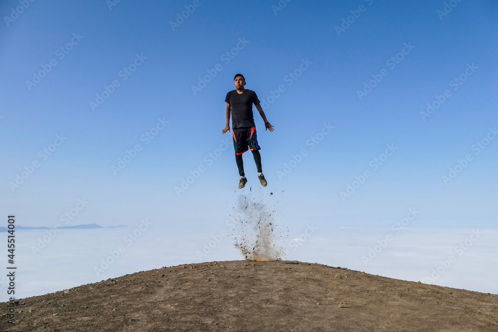 Man taking off on a hill. Background of blue sky and clouds.