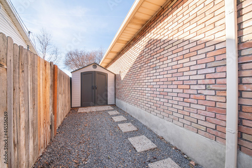 Vinyl shed in between a wooden fence and brick walls of a house