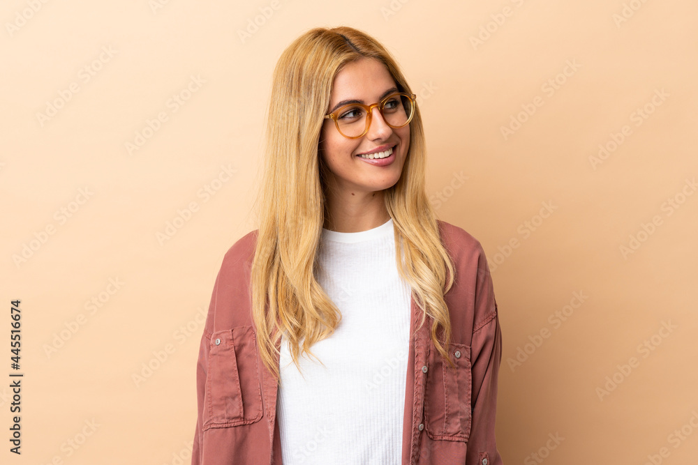 Fototapeta premium Young Uruguayan blonde woman over isolated background looking to the side and smiling