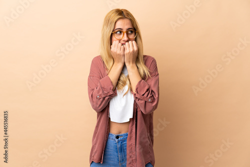 Young Uruguayan blonde woman over isolated background nervous and scared putting hands to mouth