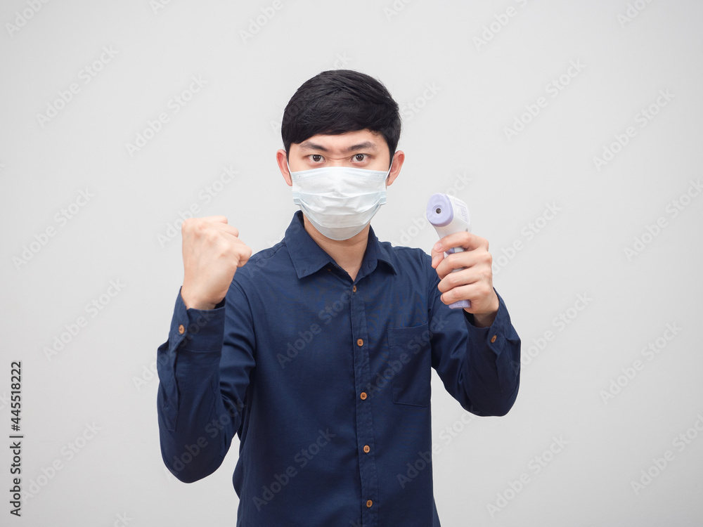 Portrait asian man wearing mask show fist up and holding infrared thermometer in hand white background Portrait asian man wearing mask show fist up and holding infrared thermometer in hand white background
