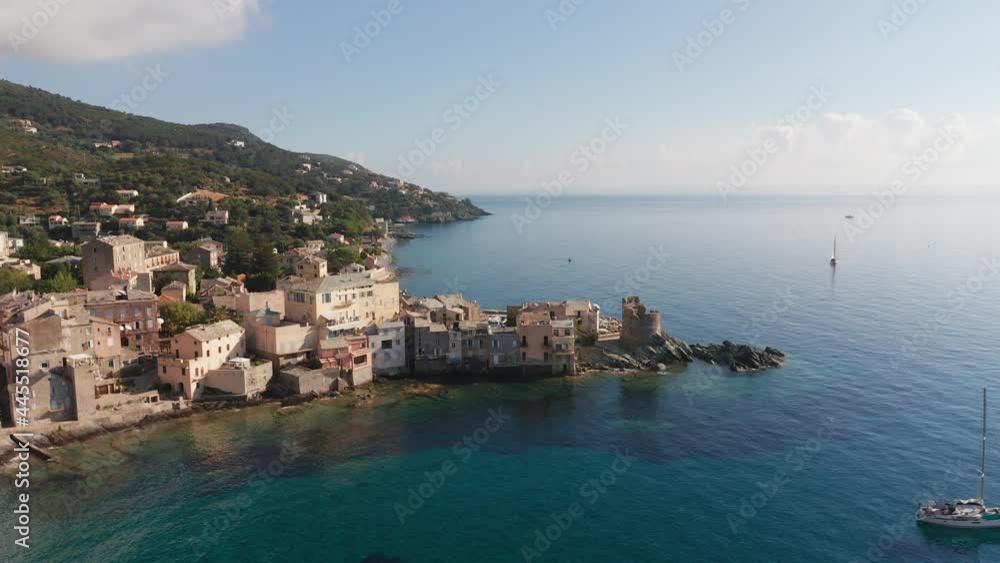 Aerial view of characteristic stone village port in corsica. Vivid blue sea. Aerial view of coast, beautiful sea, houses, trees in a sunny summer day. Aerial view of characteristic stone village port in corsica. Vivid blue sea. Aerial view of coast, beautiful sea, houses, trees in a sunny summer day.