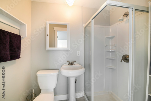 Interior of a small white bathroom with shower stall kit on the side